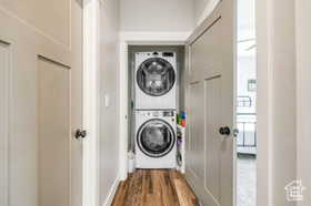 Laundry room with dark wood-style floors and estacked washer and dryer