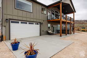 Rear view of house with board and batten siding, a patio, a garage, and concrete driveway
