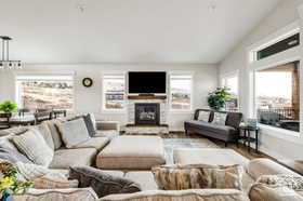 Living area with vaulted ceiling, wood finished floors, and a glass covered fireplace