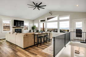 Living area featuring wood finished floors, a glass covered fireplace, vaulted ceiling, and a ceiling fan