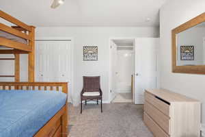 Bedroom with light colored carpet, ceiling fan, a closet, and ensuite bath