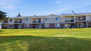 Rear view of property featuring board and batten siding, a balcony, and a yard