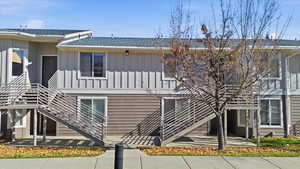 Back of house with stairs, board and batten siding, and a shingled roof