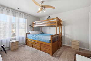 Carpeted bedroom featuring ceiling fan and baseboards