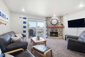 Living room featuring carpet flooring and a stone fireplace