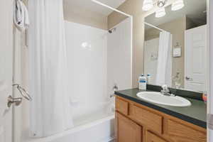 Bathroom featuring shower / bathtub combination with curtain and vanity