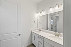 Full bath featuring double vanity and baseboards