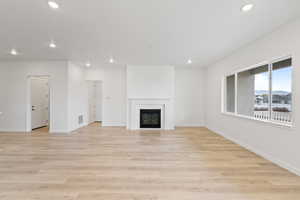 Unfurnished living room with recessed lighting, a glass covered fireplace, and light wood-style flooring