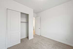 Unfurnished bedroom with light carpet and a closet