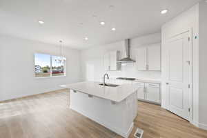 Kitchen featuring white cabinetry, pendant lighting, decorative backsplash, a kitchen island with sink, and recessed lighting