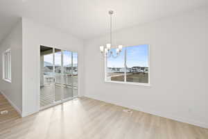 Unfurnished dining area with a chandelier, light wood-style flooring, and a residential view