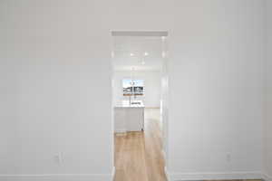 Hall featuring light wood finished floors and a chandelier