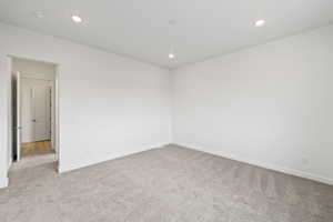 Empty room with light carpet and recessed lighting