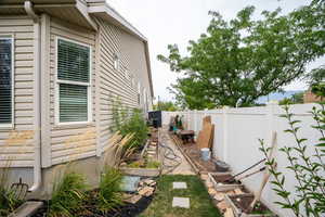 View of side of home with a fenced backyard and a garden