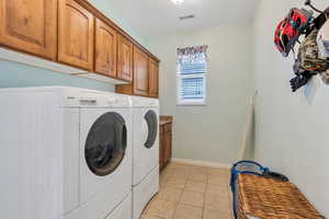 Laundry area with light tile patterned flooring, separate washer and dryer, and cabinet space