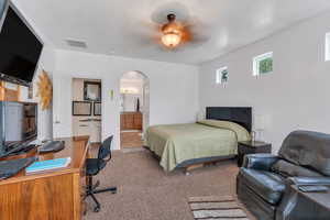 Primary Bedroom featuring carpet floors, arched walkways, a ceiling fan, a desk, and connected bathroom