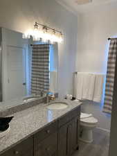 Bathroom featuring dark wood-style flooring, double vanity, and a shower with shower curtain