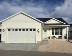 View of front of property featuring a porch, driveway, and an attached garage