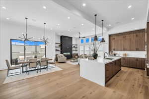 Kitchen with open floor plan, a chandelier, ceiling fan, light stone counters, and light wood-style flooring