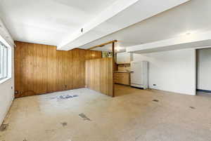 Below grade area featuring wooden walls and freestanding refrigerator