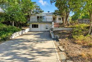 View of front facade featuring driveway and a balcony