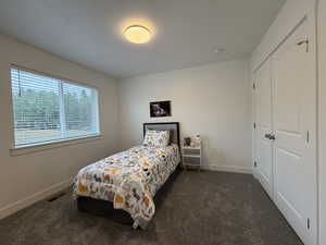 Bedroom with a closet and dark carpet
