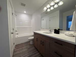 Full bath with vanity, shower / bath combination, and dark wood-style floors