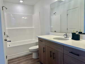 Full master bath featuring vanity, washtub / shower combination, and dark wood-type flooring and an extra closet for storage
