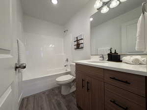 Bathroom featuring vanity, shower / washtub combination, and dark wood finished floors