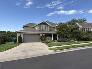Traditional-style house featuring a porch, a front yard, driveway, and stucco siding