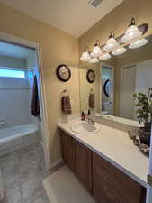Bathroom featuring vanity, shower / bathtub combination with curtain, and light tile patterned floors