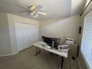 Office space with carpet, a textured ceiling, and a ceiling fan