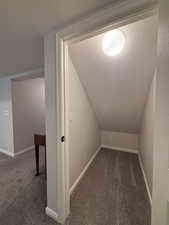Bonus room featuring dark colored carpet, a textured ceiling, and vaulted ceiling