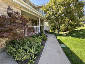 View of exterior entry featuring brick siding, a porch, and a lawn