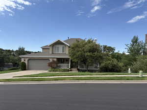 View of front of property with a porch, driveway, a front lawn, and a garage