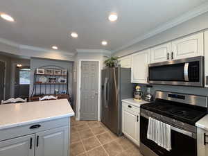 Kitchen featuring stainless steel appliances, crown molding, recessed lighting, light tile patterned flooring, and backsplash