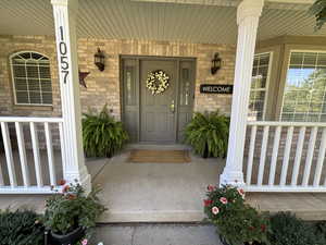 Entrance to property with covered porch and brick siding