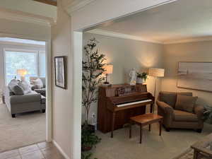Living area featuring light colored carpet, crown molding, and light tile patterned flooring