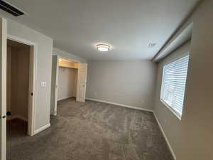 Unfurnished bedroom with dark colored carpet and a spacious closet