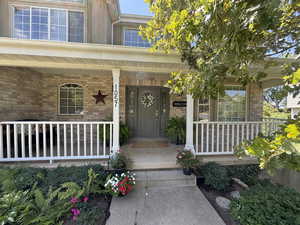 Entrance to property with a porch and brick siding
