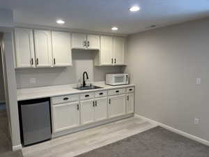 Kitchen featuring white cabinets, light countertops, stainless steel dishwasher, recessed lighting, and white microwave