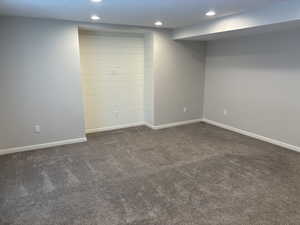 Finished below grade area with dark carpet and recessed lighting