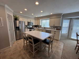 Kitchen featuring crown molding, recessed lighting, stainless steel appliances, a textured ceiling, and light tile patterned floors