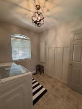 Bedroom featuring washer / dryer, light tile patterned floors, a textured ceiling, and a chandelier
