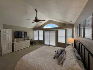 Bedroom featuring vaulted ceiling, carpet flooring, a textured ceiling, and a ceiling fan