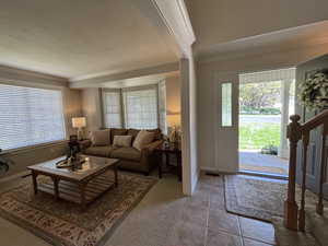 Carpeted living area with ornamental molding, tile patterned floors, stairs, and a textured ceiling