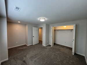 Unfurnished bedroom with dark carpet and a closet