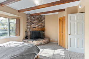 Bedroom featuring carpet flooring, a fireplace, and beamed ceiling