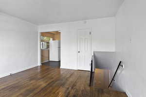 Unfurnished room featuring dark wood finished floors and baseboards