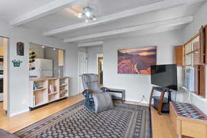 Living room featuring beam ceiling, light wood-style flooring, and a desk